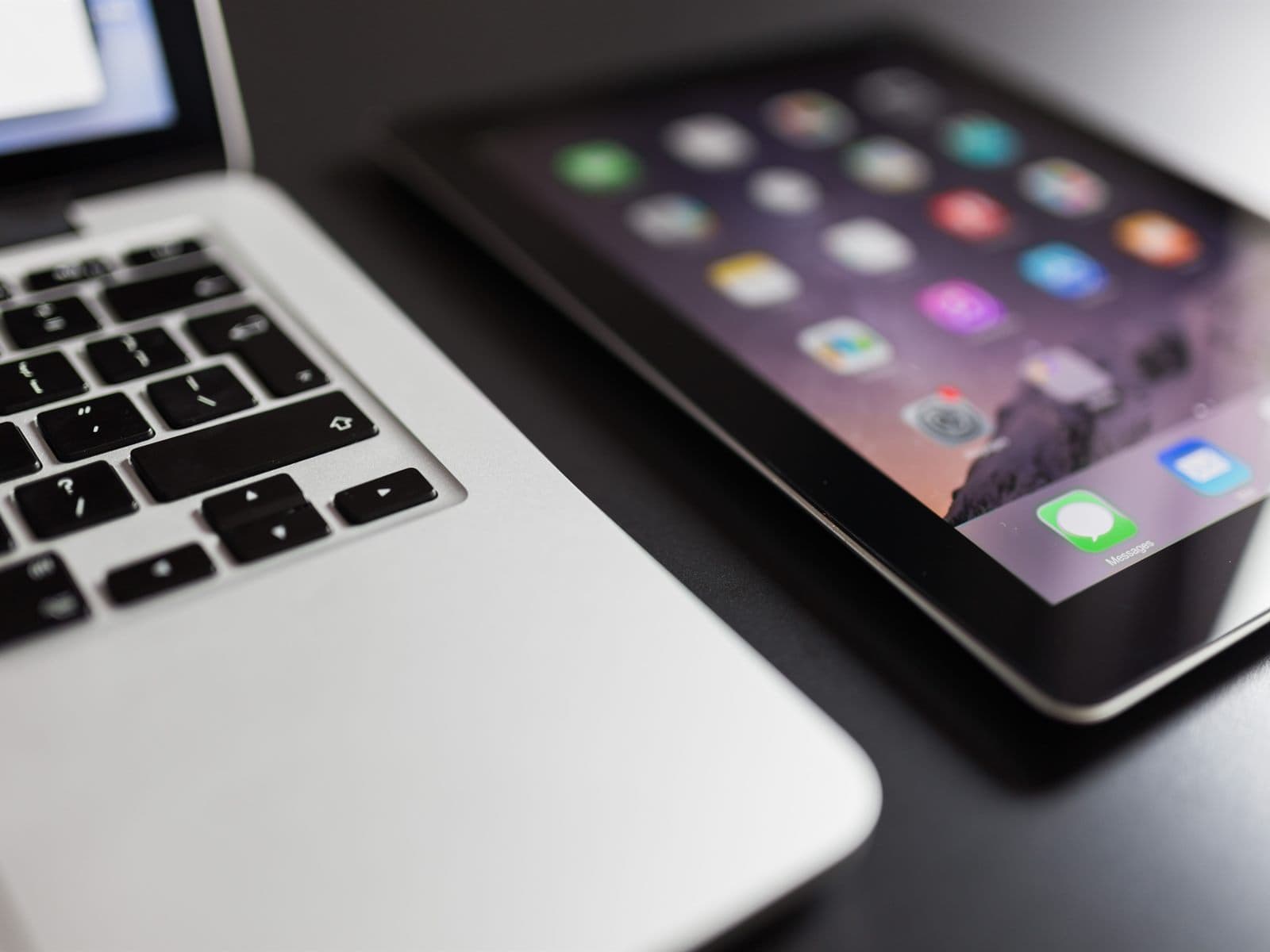 A laptop and a tablet side by side on a dark desk